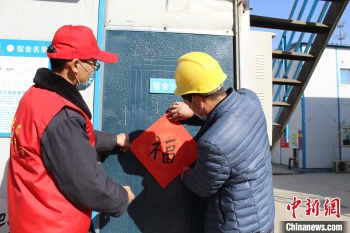 就地过年农民工和英志愿者一起贴福字。 中建五局供图 摄 就地过年农民工和英志愿者一起贴福字。 中建五局供图 摄